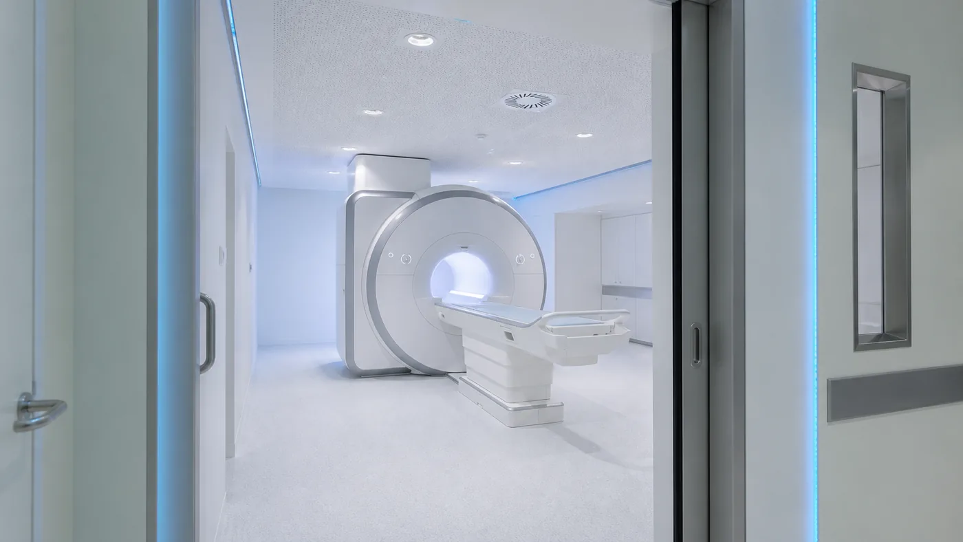 Salle d'imagerie médicale moderne et lumineuse avec un appareil d'IRM, vue depuis le couloir